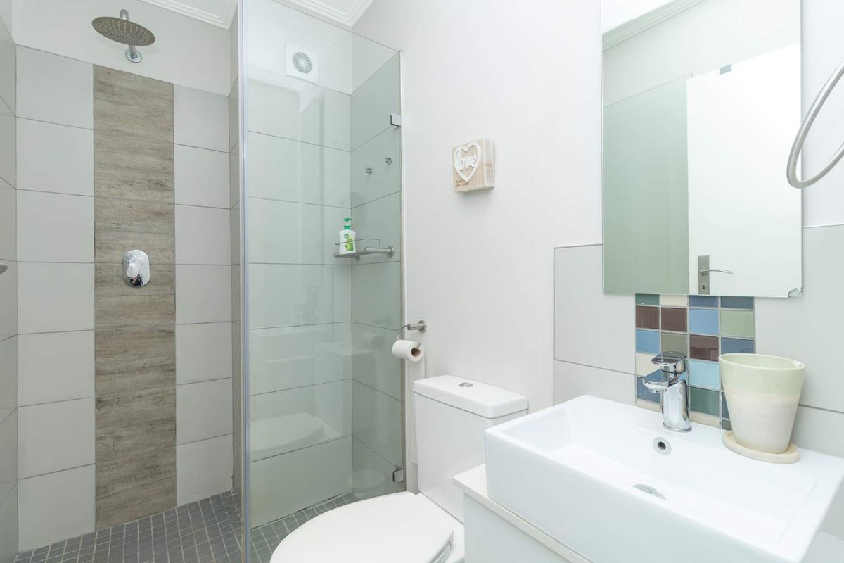 Modern bathroom featuring a glass-enclosed shower with rainfall showerhead, a contemporary vanity basin, and decorative mosaic tile accents.