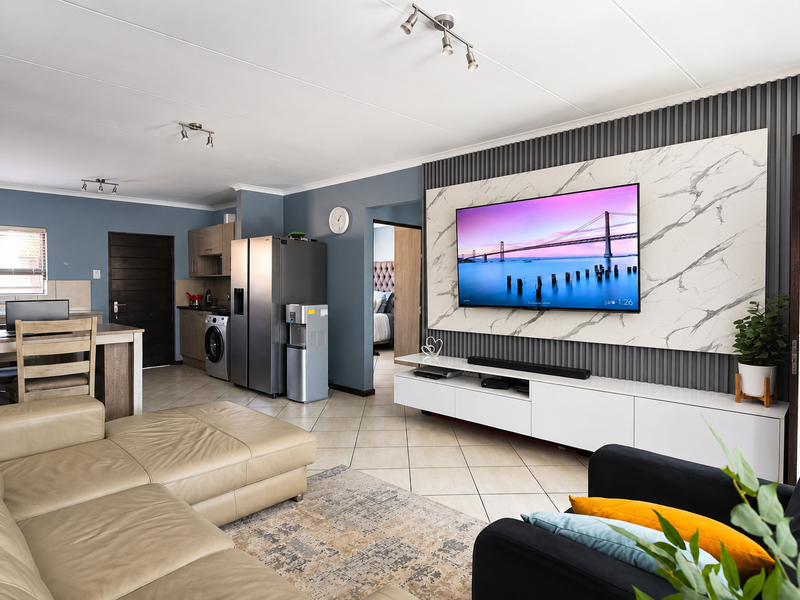 Spacious open-plan living area featuring a modern marble-effect feature wall, slatted paneling, and tiled flooring, seamlessly connecting to the kitchen space.