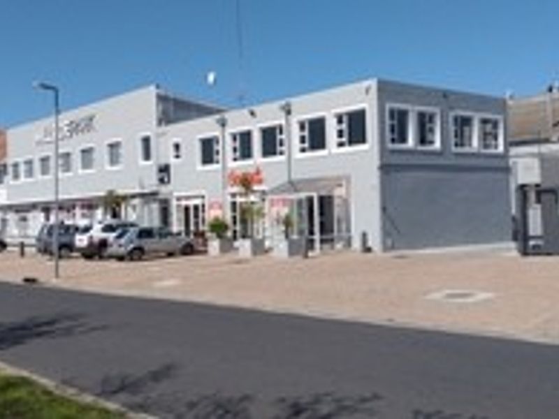 Front exterior view of a multi-story office complex featuring a paved parking area and prominent building signage.