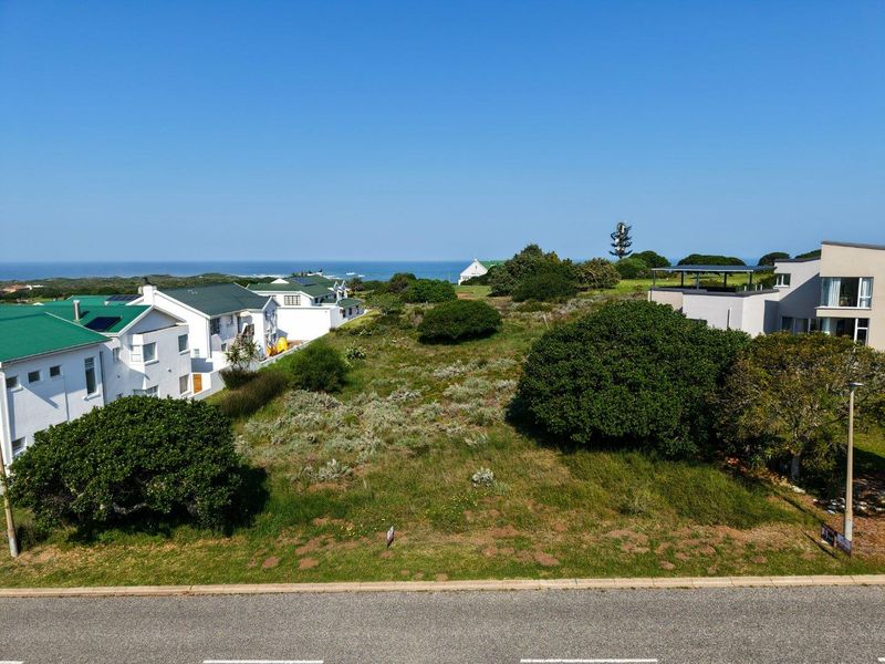 An aerial view of a vacant residential plot situated in a coastal neighborhood, offering potential for development with surrounding established homes.