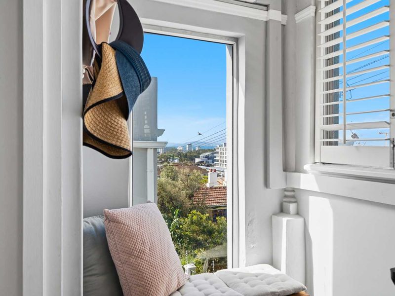 A bright interior space featuring white plantation shutters and crown molding, framing a scenic outdoor view.