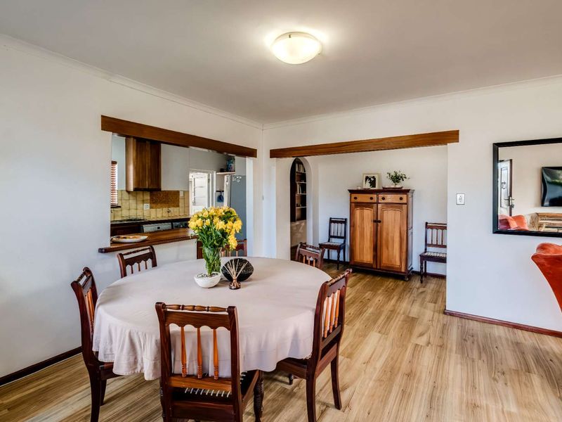 Open plan dining area featuring laminate flooring, a timber beam accent, and a convenient pass-through window connecting to the kitchen space.