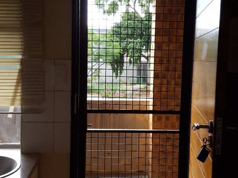 A functional kitchen area featuring tiled flooring, a sink, and a secure metal gate leading to an outdoor space.