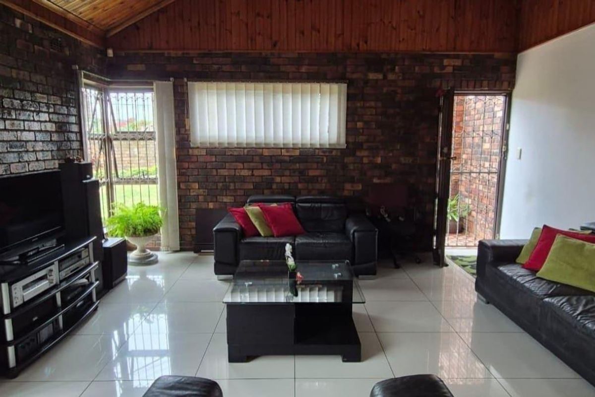 Spacious living room featuring exposed brick walls, a high timber vaulted ceiling, and polished floor tiles, offering a rustic yet modern aesthetic.