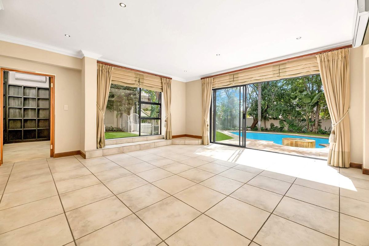 Spacious living area featuring large sliding glass doors opening to a swimming pool, tiled flooring, and recessed lighting.