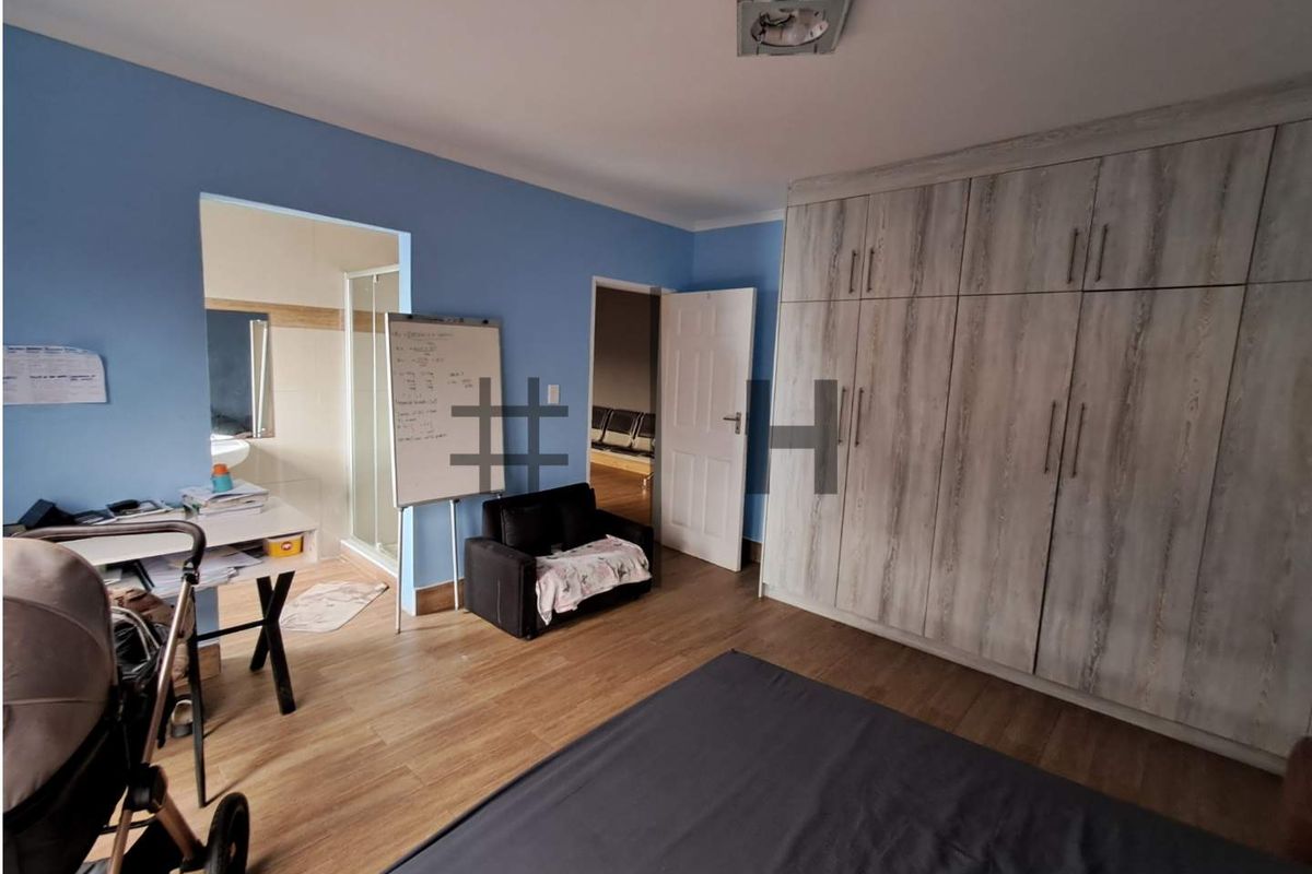 A bedroom featuring built-in wooden cabinetry and an en-suite bathroom access, finished with wood-look flooring.