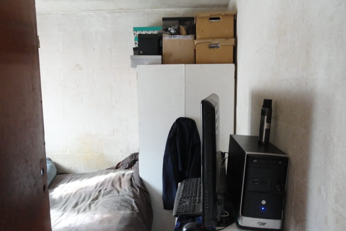 A compact bedroom featuring basic wall finishes and a built-in storage unit, requiring cosmetic updates to improve the overall living environment.