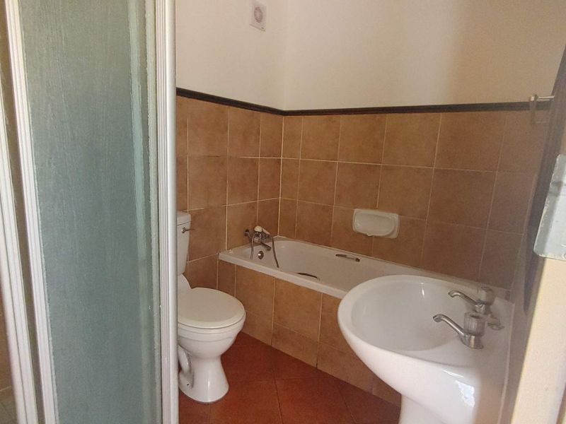 A functional bathroom featuring a bathtub, pedestal basin, toilet, and a separate shower enclosure with tiled finishes throughout.