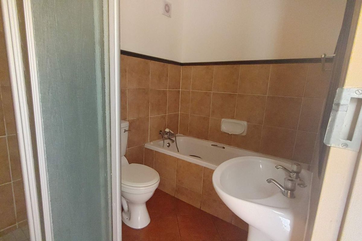 A functional bathroom featuring a bathtub, pedestal basin, toilet, and a separate shower enclosure with tiled finishes throughout.