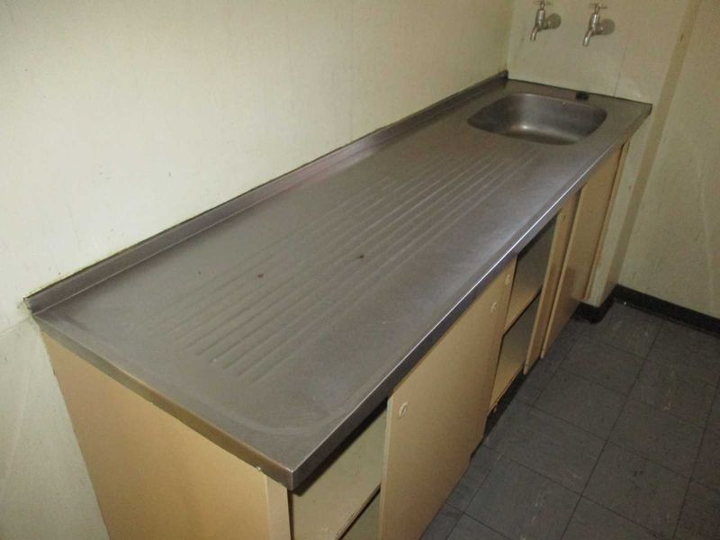 A functional laundry area featuring a stainless steel sink, built-in cabinetry, and tiled flooring, providing a practical utility space.