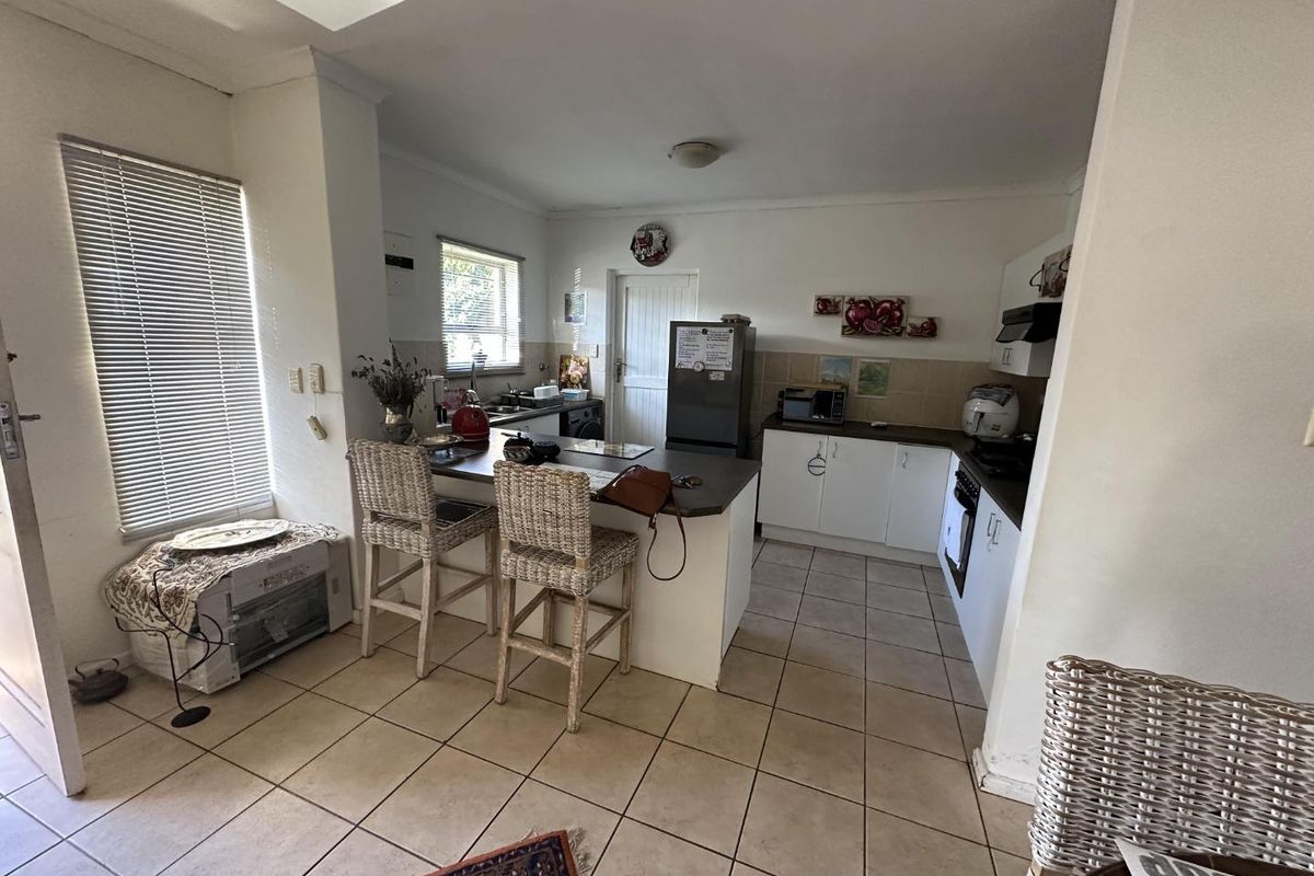 A functional kitchen featuring tiled flooring, built-in cabinetry, a breakfast bar, and integrated appliances, offering a practical layout for daily use.