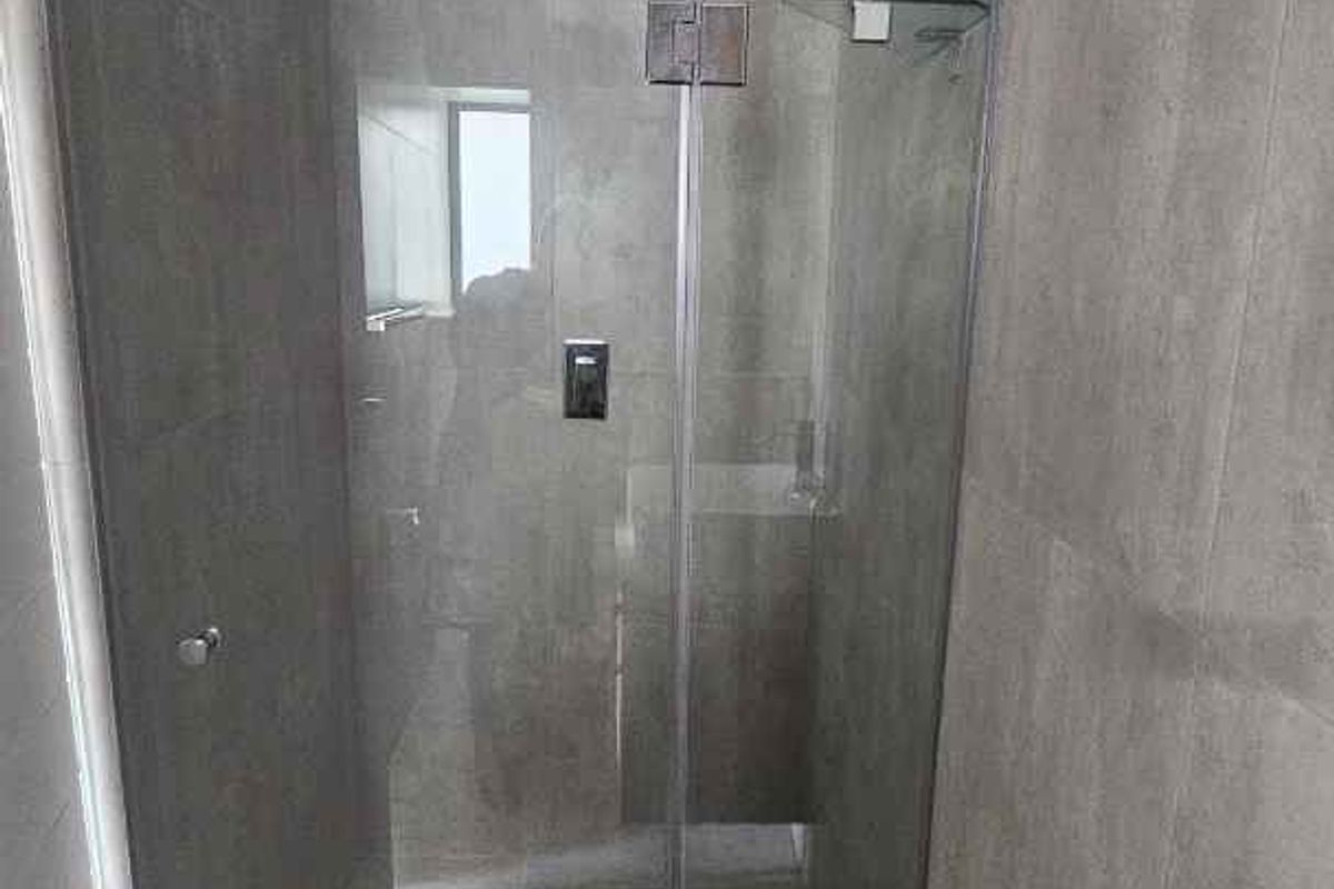 Modern bathroom featuring a walk-in shower with a glass screen, rainfall showerhead, and contemporary grey wall and floor tiling.