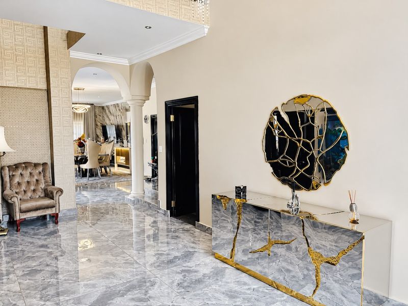 Elegant entrance hallway featuring polished marble-look flooring, decorative arched architectural details, and sophisticated textured wall finishes leading into the main living area.