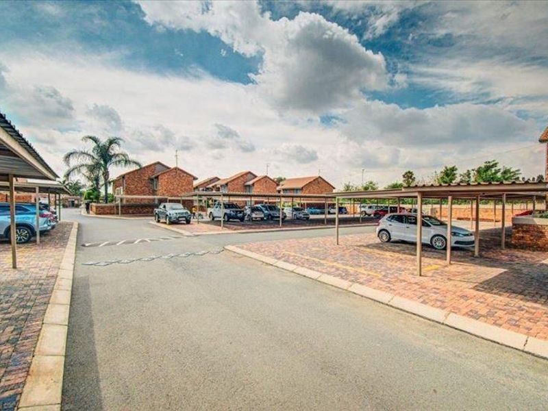 A view of the townhouse complex entrance featuring paved driveways and covered carport parking bays for residents.