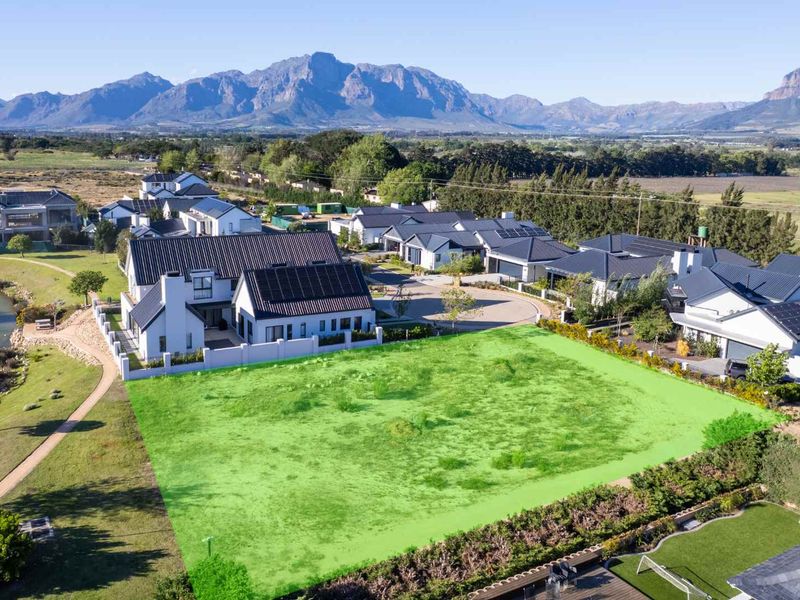 An aerial view of a vacant residential plot in a scenic estate, highlighting the available land area with mountain views.