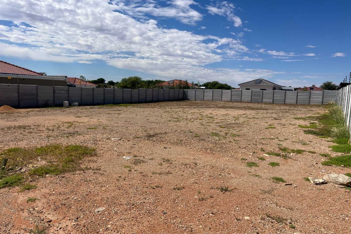 A vacant residential plot enclosed by precast concrete boundary walls and electric fencing, offering a clear space ready for development.