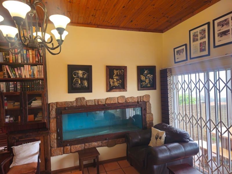 Living room featuring a unique built-in aquarium with stone surround, timber ceiling, and direct access to the exterior through a security gate.