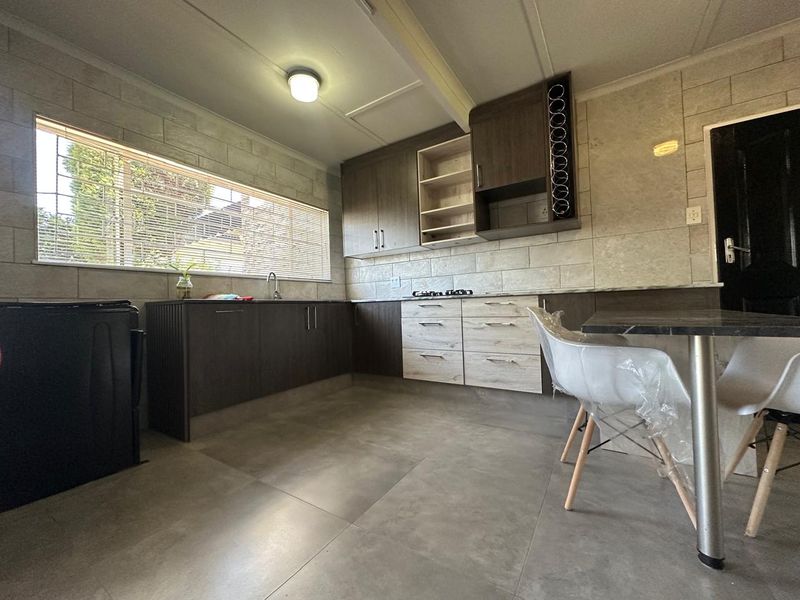 Modern kitchen featuring dark and light wood-toned cabinetry, tiled splashbacks, a gas hob, and large format floor tiles.