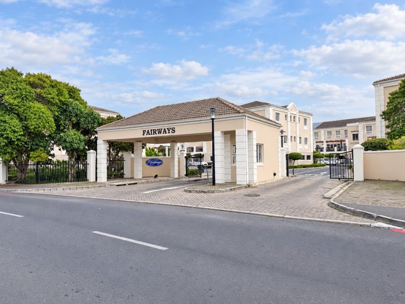 The main entrance to the Fairways office complex, featuring a secure gated access point, guard house, and paved driveway.