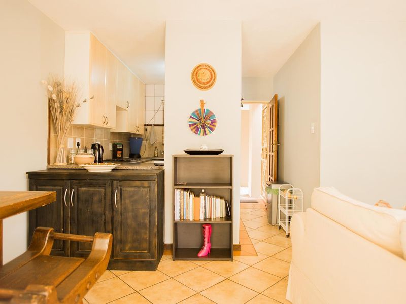 Open plan living area featuring tiled flooring and a compact kitchen with built-in cabinetry and granite countertops.