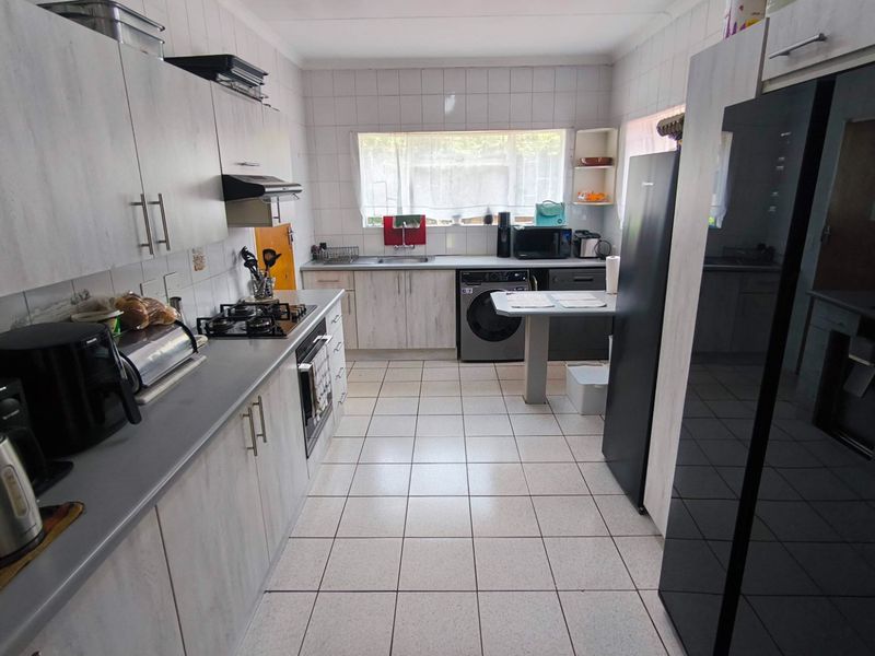 Functional kitchen featuring light wood-look cabinetry, gas hob, built-in oven, extractor fan, and tiled finishes throughout.