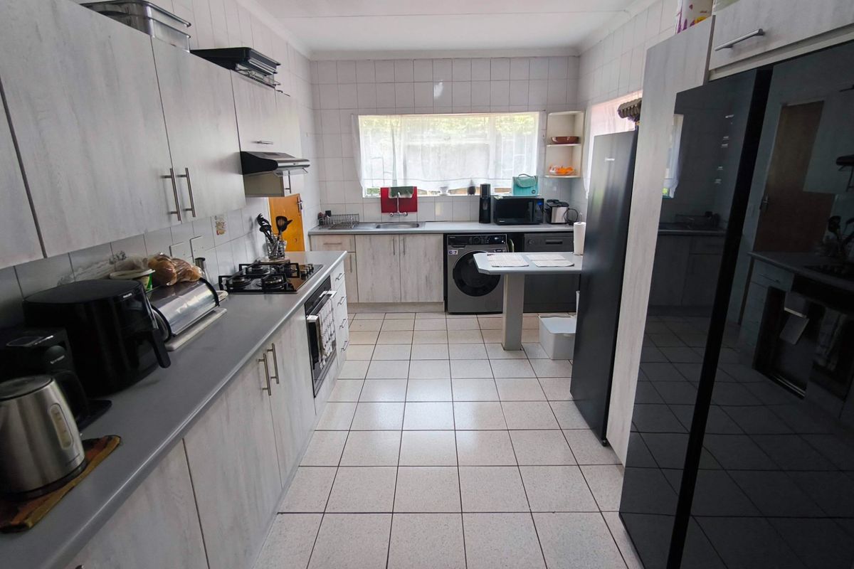 Functional kitchen featuring light wood-look cabinetry, gas hob, built-in oven, extractor fan, and tiled finishes throughout.