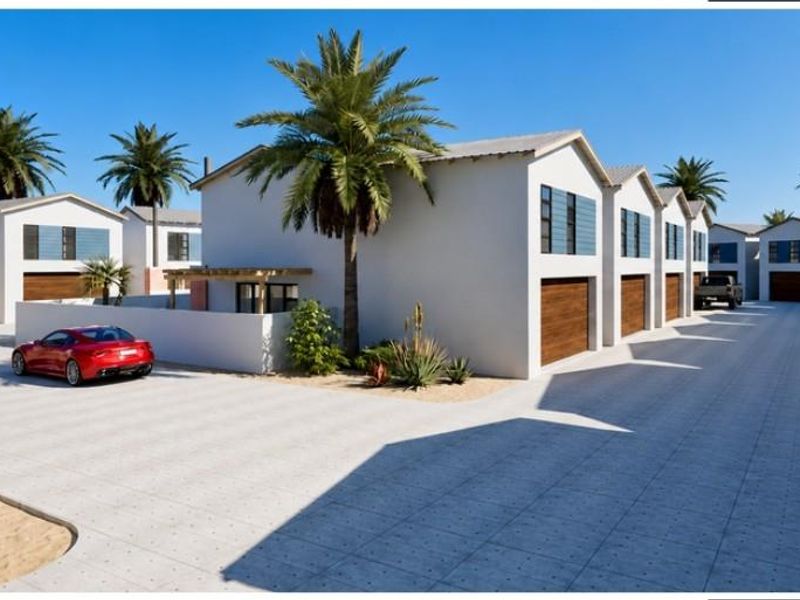A modern townhouse complex featuring a paved driveway, multiple garage access points, and clean architectural lines in a well-maintained residential setting.