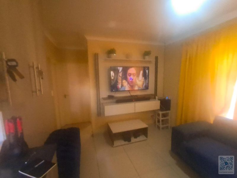 A living room featuring a built-in media unit and tiled flooring, providing a functional space for entertainment.