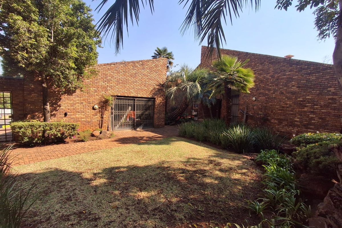 A private rear garden area featuring a classic brick facade, paved pathways, and established landscaping, providing a tranquil outdoor space.
