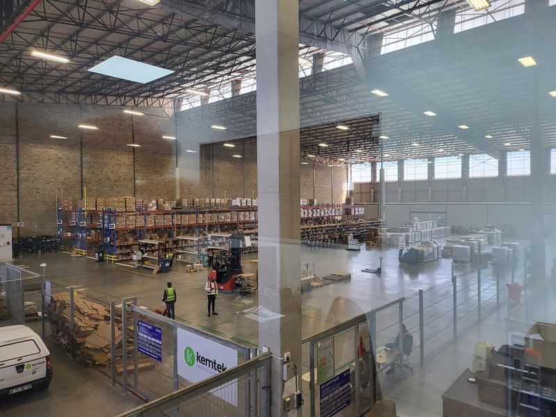 Spacious industrial warehouse facility featuring high ceilings, exposed steel trusses, concrete flooring, and extensive pallet racking systems for storage and logistics operations.