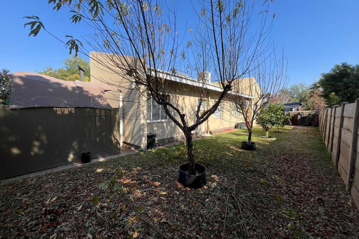 Rear exterior view of the property featuring a garden area, plastered wall finish, and precast concrete boundary walling.