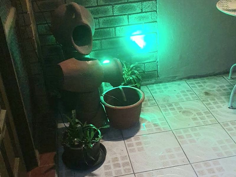A covered patio area featuring brick wall detailing and tiled flooring, illuminated by decorative green lighting.
