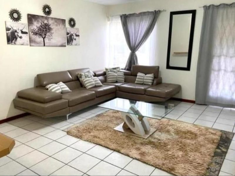 A living room area featuring tiled flooring and a sliding glass door providing access to the exterior.