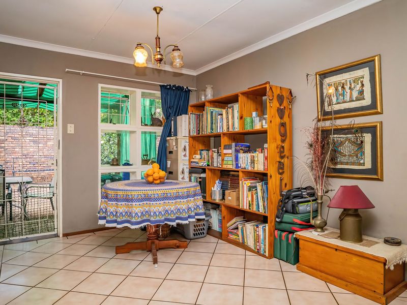 A living area featuring tiled flooring, a coved ceiling, and direct access to an outdoor patio through a security-fitted door.