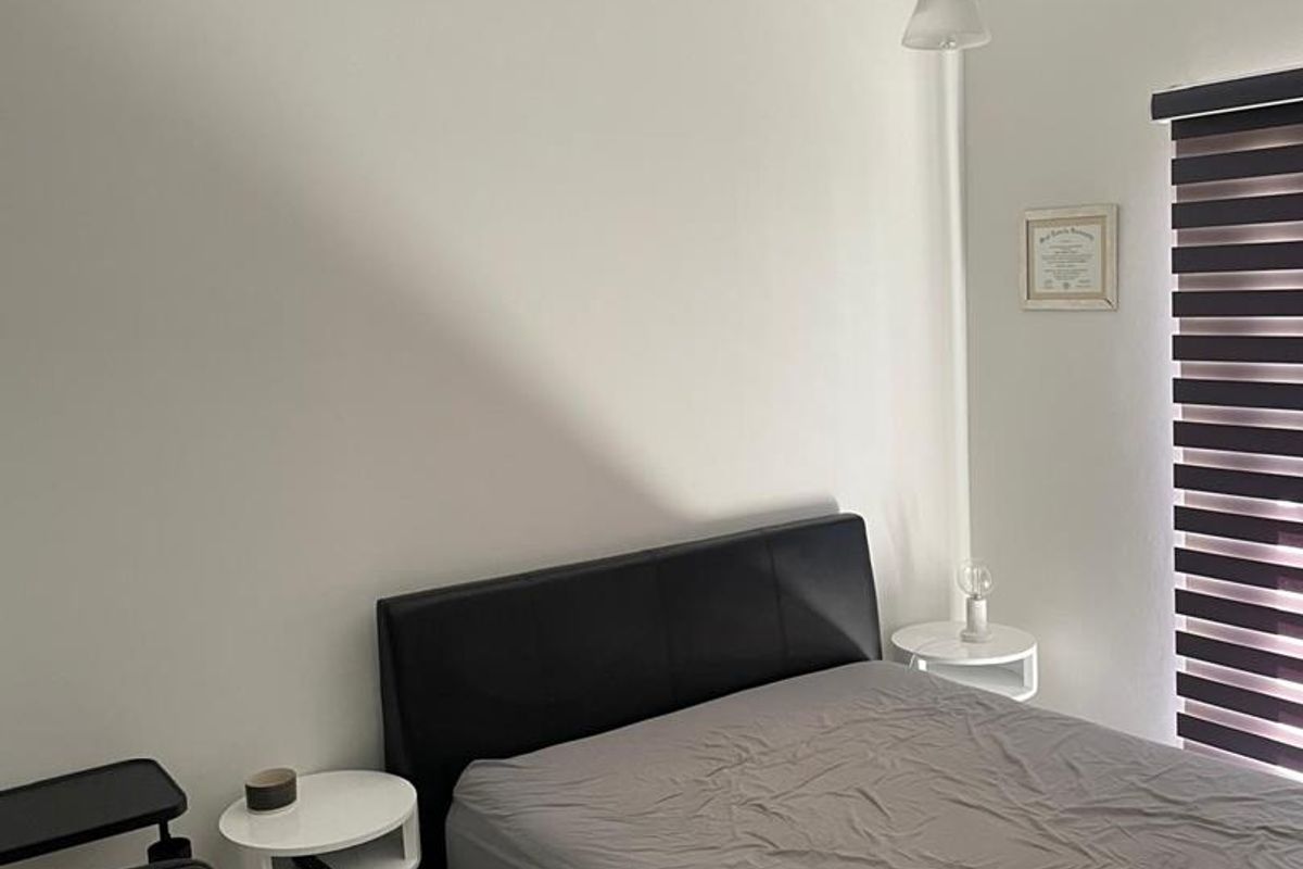 A bedroom featuring tiled flooring, a pendant light fixture, and a window fitted with a modern zebra-style roller blind.