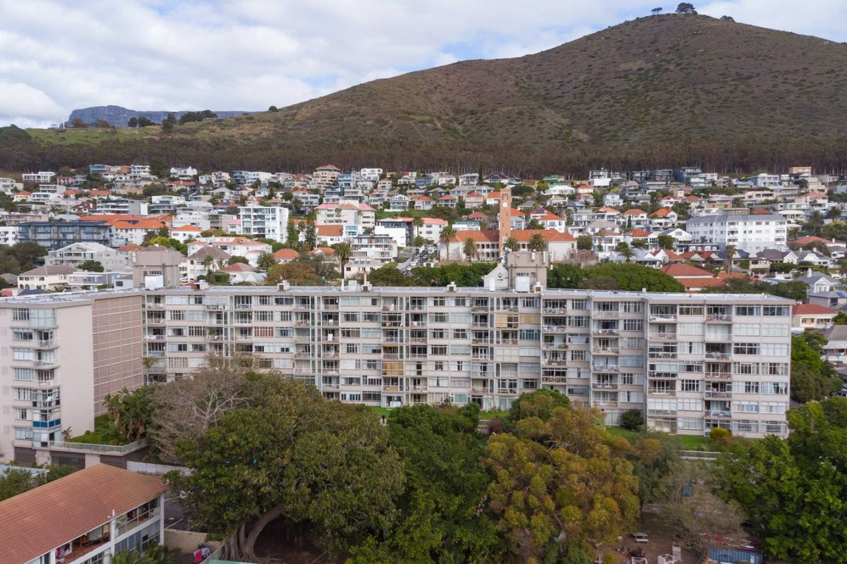 Aerial view of a large multi-story apartment complex situated in a residential neighborhood with mountain views.