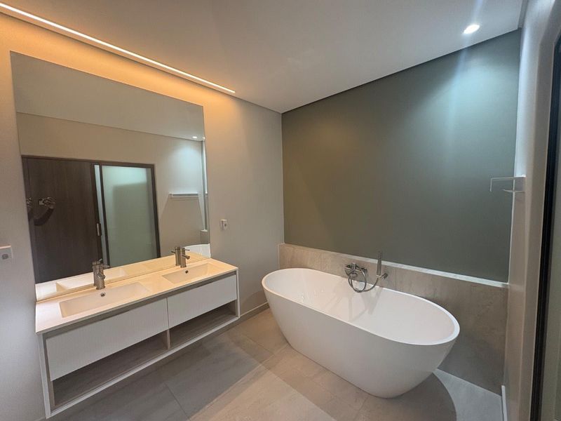 Modern bathroom featuring a sleek double vanity, a contemporary freestanding bathtub, and elegant recessed lighting in a clean, minimalist design.
