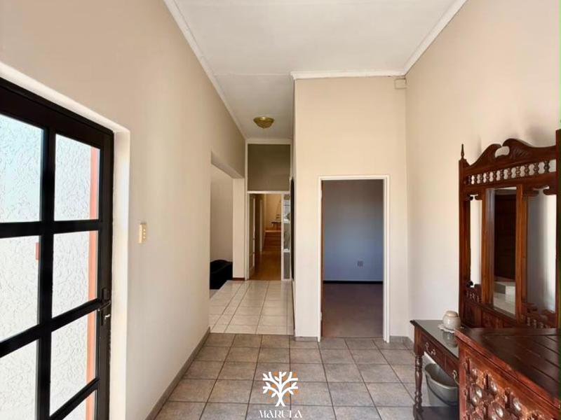 A tiled hallway providing access to multiple rooms, featuring neutral wall tones and coved ceiling details.