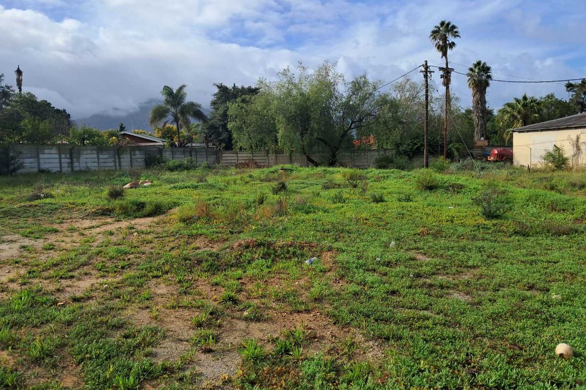 A vacant residential plot featuring established perimeter walling, mature trees, and mountain views, offering a blank canvas for future development.