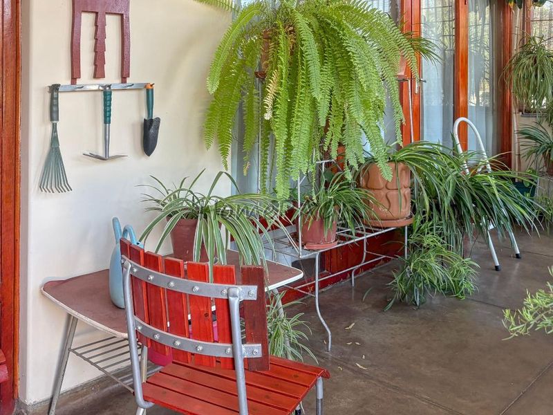 A covered patio area featuring tiled flooring and wooden framed glass doors providing access to the interior.