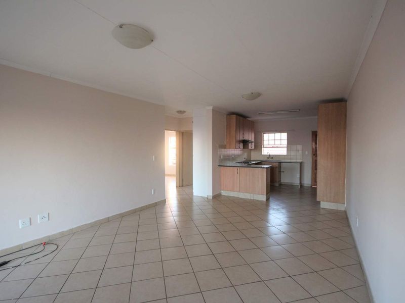 Open-plan living area featuring tiled flooring and a functional kitchen with built-in cabinetry, hob, and extractor fan.
