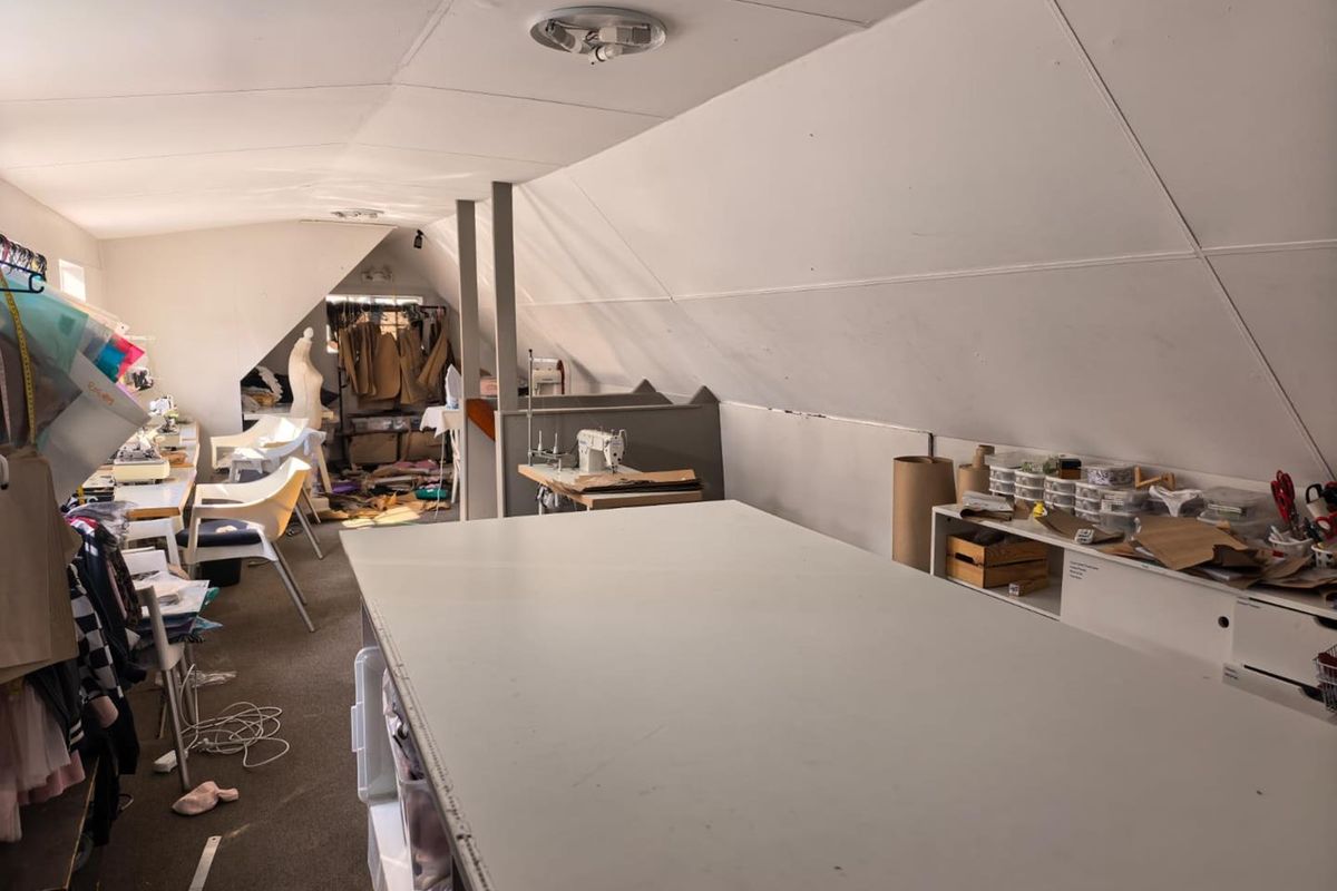 An attic-style office space featuring sloped ceilings, built-in shelving, and ample workspace, suitable for a creative studio or professional office environment.