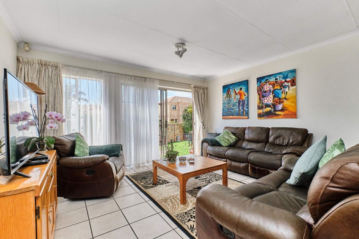 A bright living room featuring tiled flooring and a sliding glass door that provides direct access to the rear garden area.