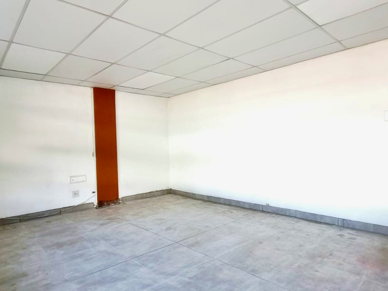 An empty industrial office space featuring a suspended ceiling, tiled flooring, and neutral white walls, ready for custom fit-out.