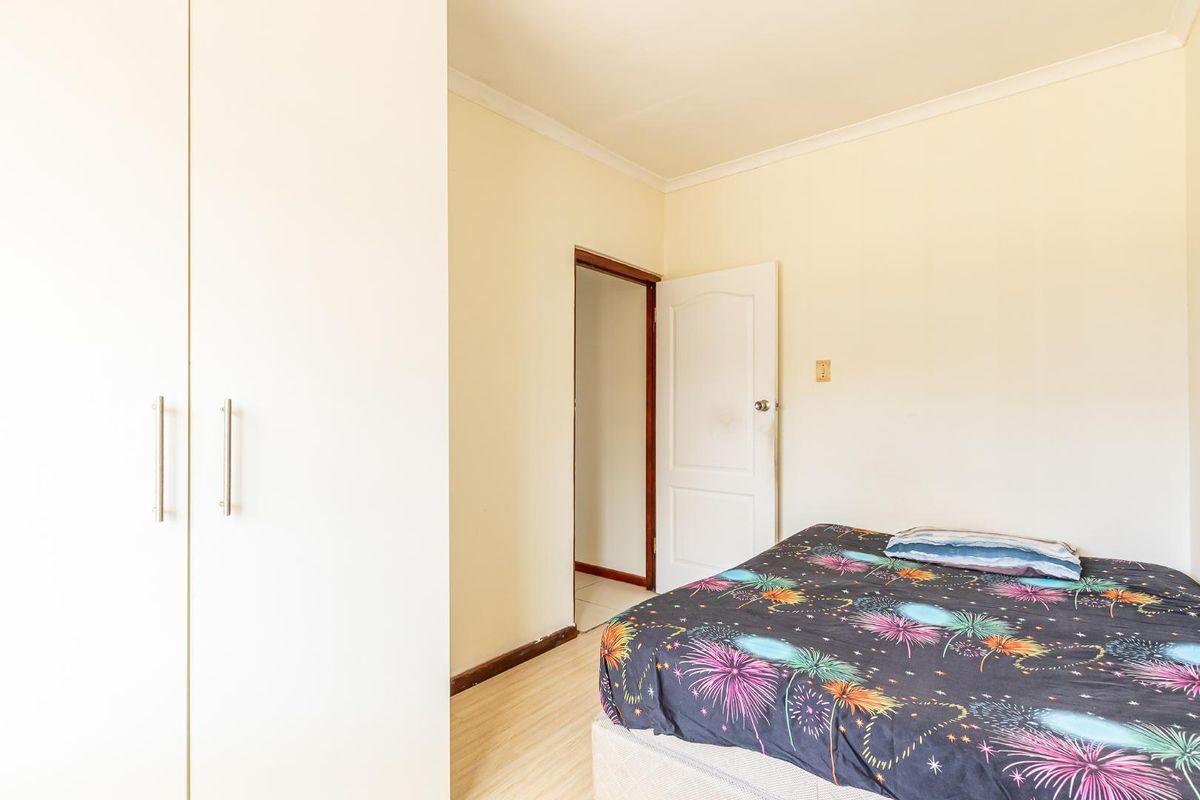 A functional bedroom featuring built-in wardrobes, light laminate flooring, and neutral wall finishes, providing a clean and simple living space.