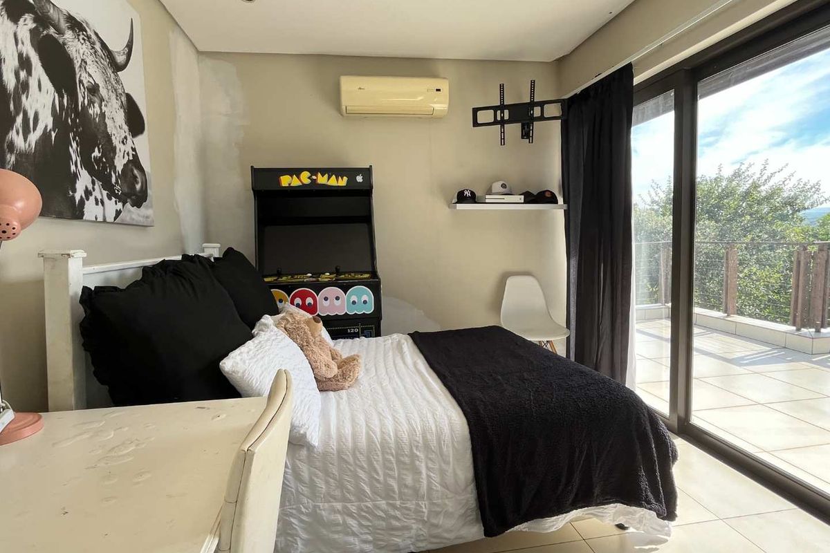 Bedroom featuring tiled flooring, wall-mounted air conditioning, and large sliding glass doors providing access to an outdoor balcony area.