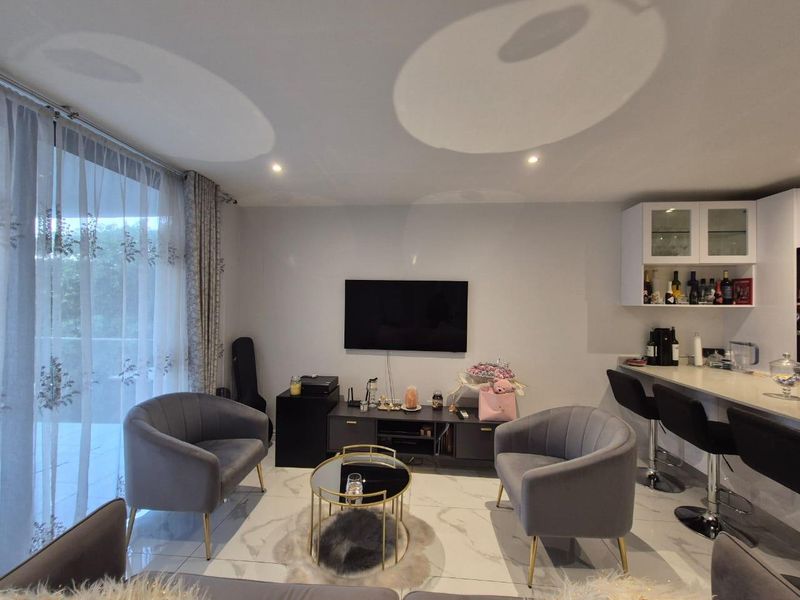 Modern open-plan living area featuring marble-look tiled flooring, recessed lighting, and a built-in breakfast bar with overhead cabinetry.