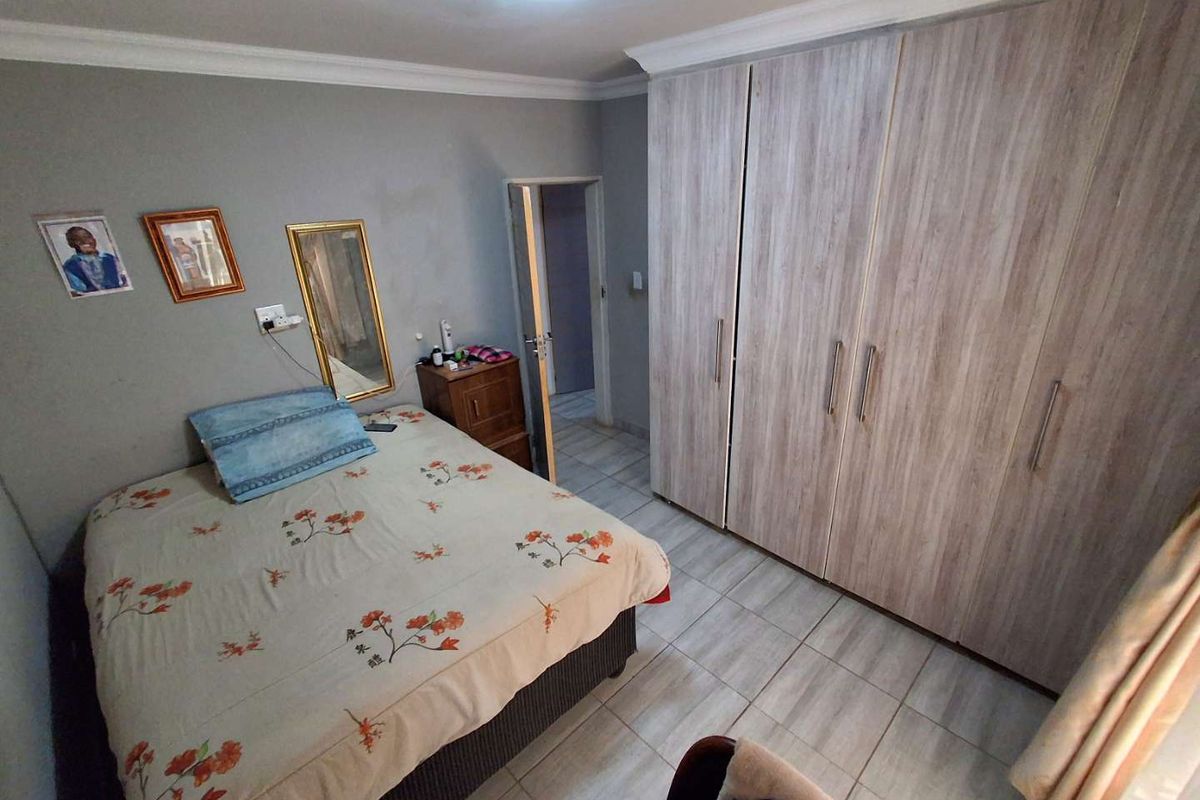 A bedroom featuring built-in wooden wardrobes, tiled flooring, and crown molding.