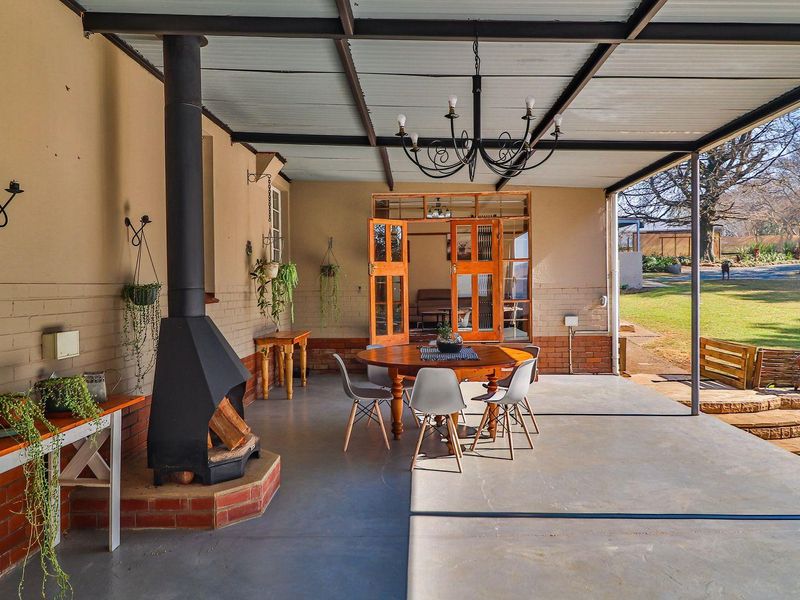 Spacious covered patio featuring a built-in fireplace, concrete flooring, and direct access to the garden through timber-framed glass doors.