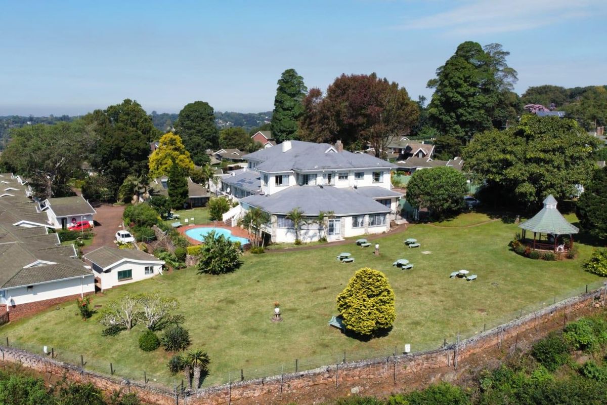 Aerial view of a large property featuring a spacious garden, swimming pool, gazebo, and multiple residential building structures.